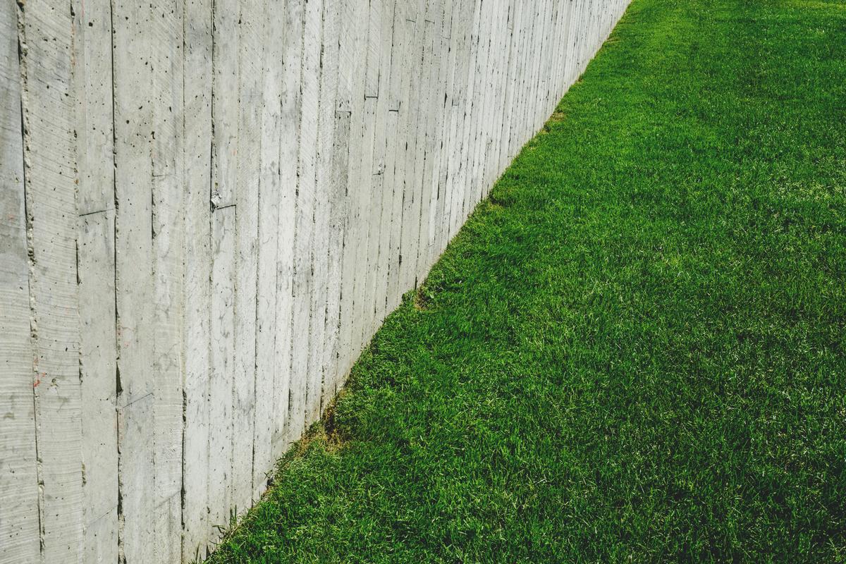 Groen gras naast een grijze betonnen muur